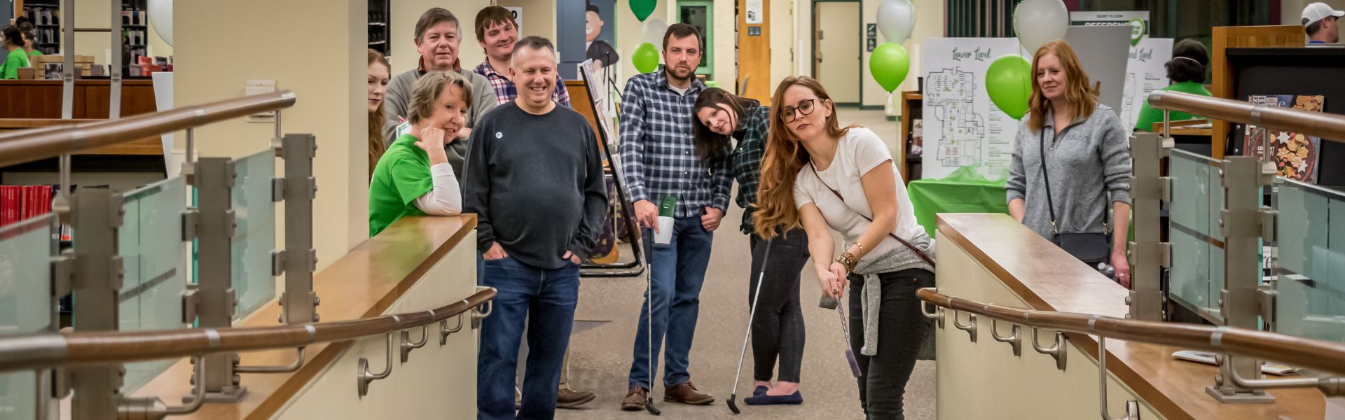 Group playing golf at Wheaton Public Library during the Mad Fore Plaid Mini Golf event