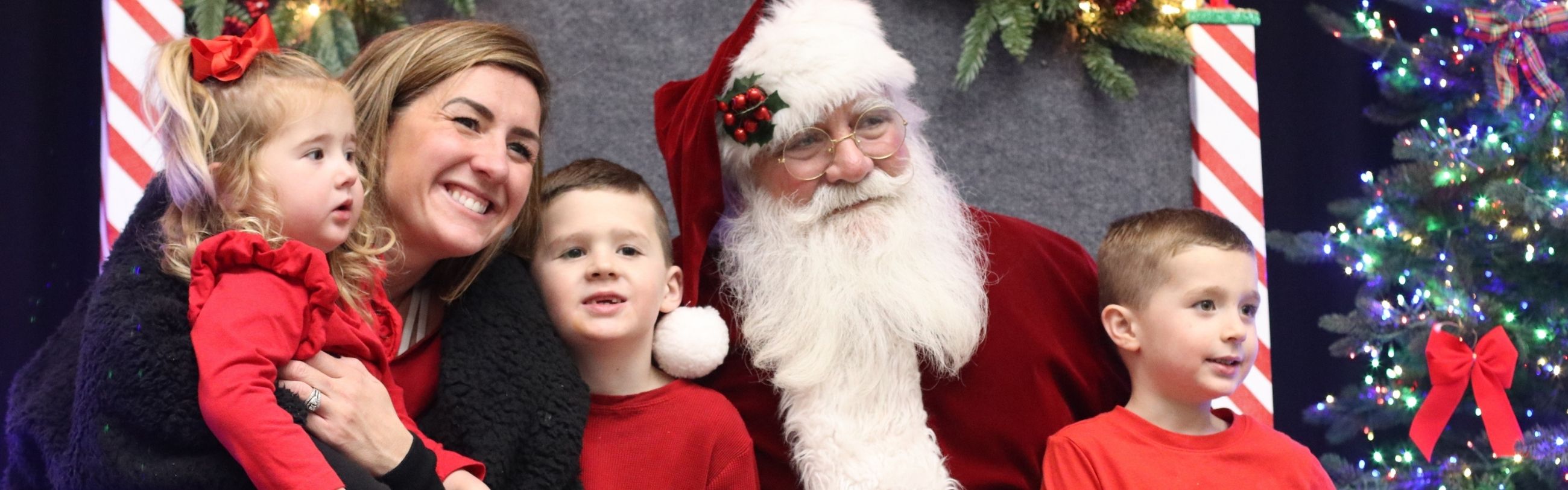 An adult with three children sitting with Santa