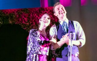 Woman and men singing on stage during Shakespeare in the Park event