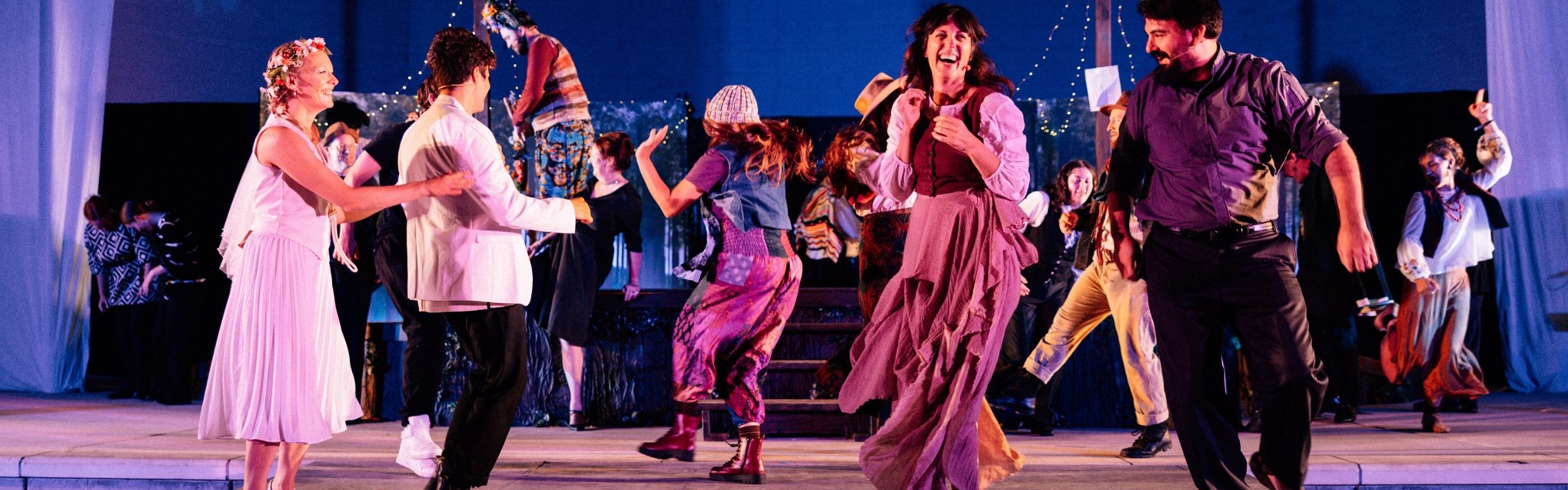 Performers dancing on stage during the Shakespeare in the Park event